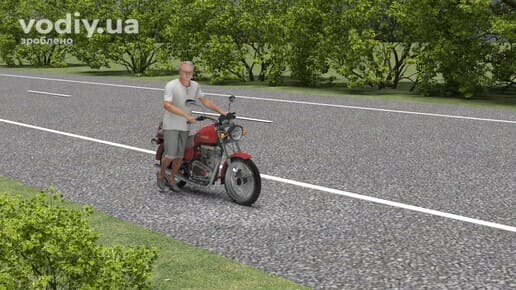 Чоловік веде мотоцикл узбіччям дороги поза населеним пунктом, статус особи в дорожньому русі згідно з ПДР.