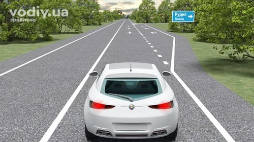 Горизонтальна дорожня розмітка 1.8 позначає межу між перехідно-швидкісною та основною смугою, білий автомобіль на дорозі поза населеним пунктом.