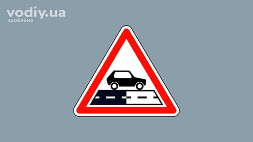 Дорожній знак 1.40 «Зміна покриття», що попереджає про перехід асфальтованої дороги у гравійну або ґрунтову.