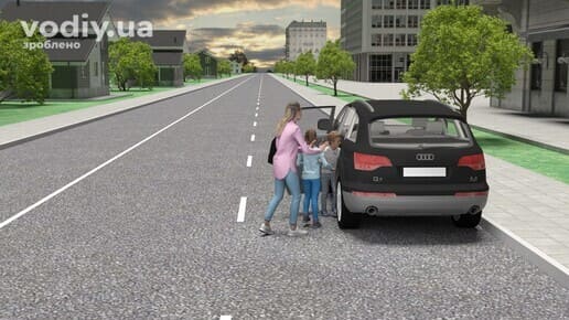 Посадка пасажирів в автомобіль з боку суміжної смуги руху, жінка з дітьми біля відчинених лівих дверей авто на дорозі.