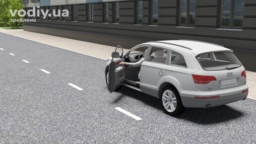 Водій відчиняє двері білого автомобіля під час руху вздовж будівлі, рука водія на дверній ручці відчинених дверей.