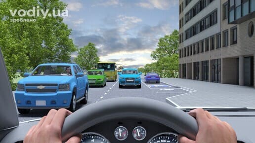 Зустрічний автомобіль на смузі руху в населеному пункті, руки водія на кермі, автобус та легкові авто на дорозі біля будинку.