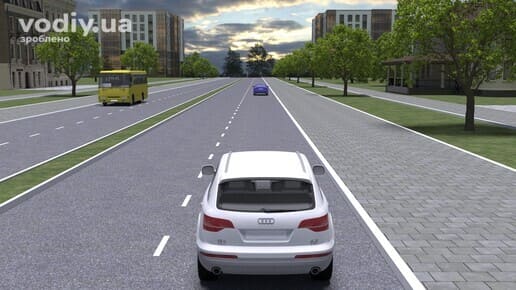 Максимальна швидкість руху в населеному пункті, дорога з розділювальною смугою, білий автомобіль та жовтий автобус у місті.