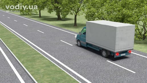 Вантажний автомобіль на дорозі з окремими проїзними частинами, розділювальна смуга з газоном та бордюром поза населеним пунктом.