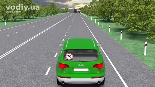 Зелений автомобіль на дорозі поза населеним пунктом, знак Обмеження максимальної швидкості 70 на задньому склі авто.