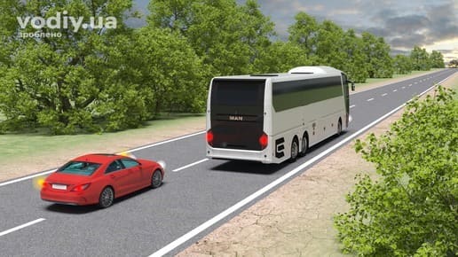 Червоний легковий автомобіль з увімкненим лівим покажчиком повороту виїжджає для обгону білого автобуса на заміській дорозі.