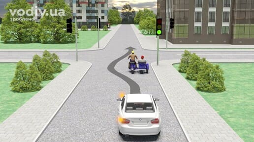 Автомобіль з увімкненим лівим покажчиком повороту та мотоцикл з коляскою перед перехрестям, зелений сигнал світлофора.