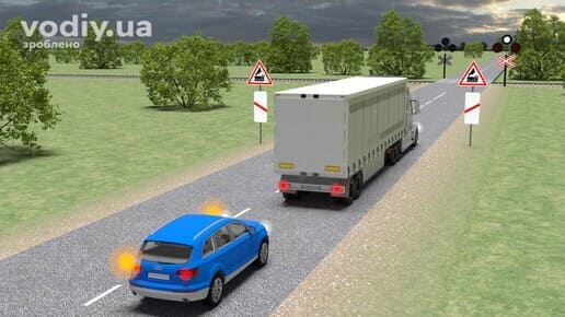 Обгін перед залізничним переїздом, дорожні знаки 1.28, 1.31.1, 1.31.4, 1.29, вантажівка та легковий автомобіль з лівим покажчиком повороту.