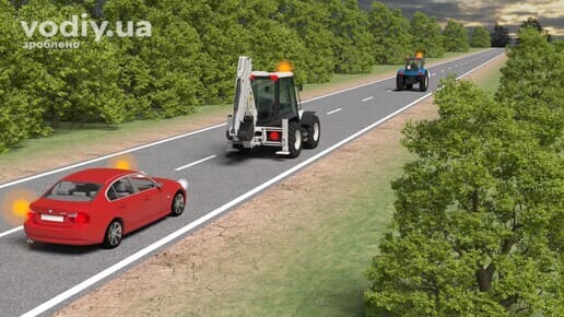 Обгін спецтехніки з увімкненими оранжевими проблисковими маячками, червоний автомобіль та трактор на дорозі поза населеним пунктом.