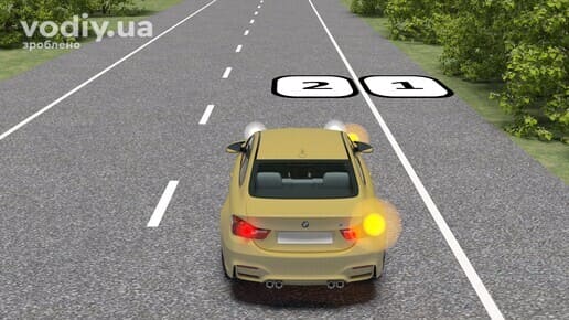 Легковий автомобіль з увімкненим правим покажчиком повороту перед вибором місця для зупинки на узбіччі або краї проїзної частини.