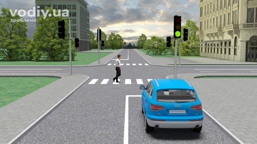 Блакитний автомобіль перед регульованим перехрестям, зелений сигнал світлофора та пішохід на пішохідному переході.
