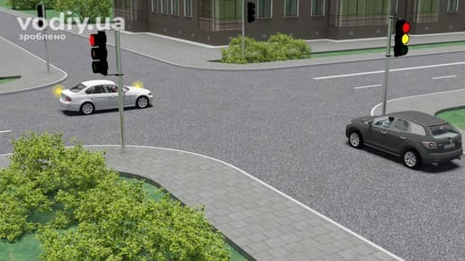 Чорний та білий автомобілі на перехресті, червоний і жовтий сигнали світлофора, біле авто завершує поворот ліворуч.