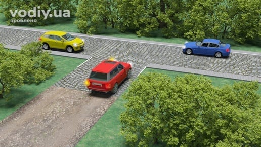 Червоний автомобіль виїжджає з ґрунтової дороги на дорогу з кам'яним покриттям, де рухаються жовтий та синій автомобілі.